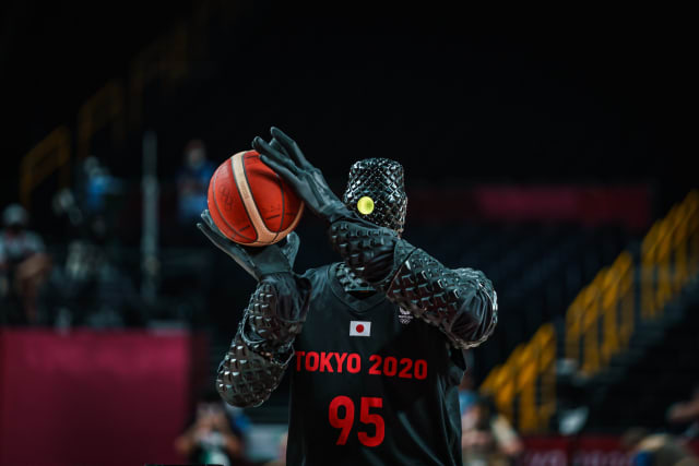 Picture of a robot at the olympic games holding a basketball, ready to shoot. It's kinda scary.